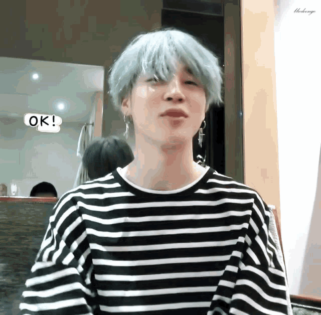 a person wearing a black and white striped shirt with a ok sticker on it
