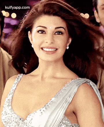 a woman is wearing a silver dress and smiling .