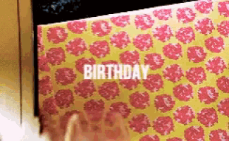 a person is wrapping a birthday present in pink and yellow