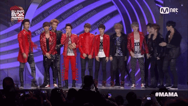 a group of young men standing on a stage with a mnet logo in the corner