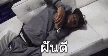a man is laying on a white couch with a foreign language written on it .