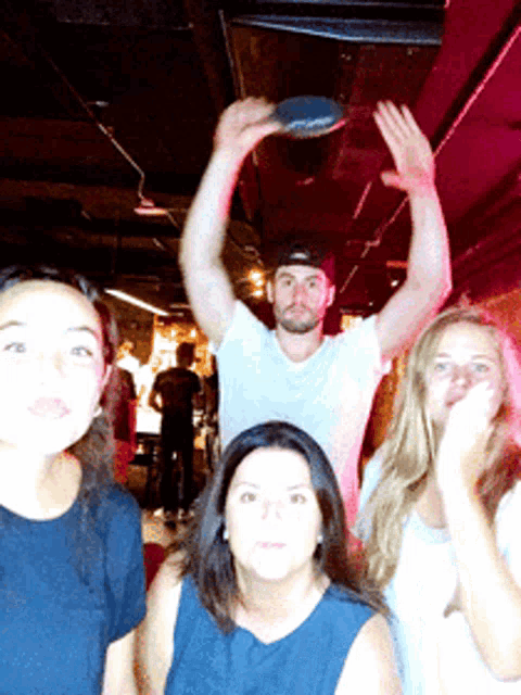 a group of people are posing for a picture and one of them is holding a ping pong paddle over his head
