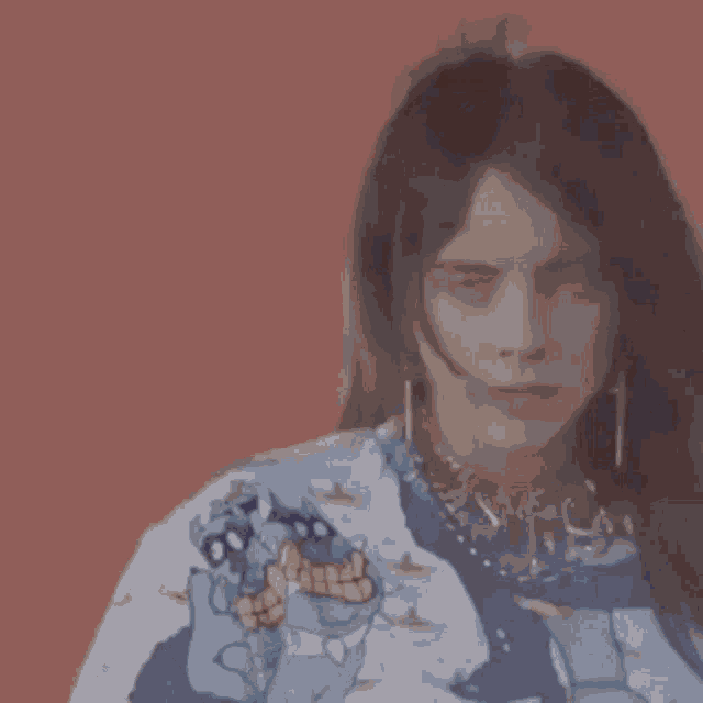 billie eilish is wearing a sweater with a monster on it and earrings .