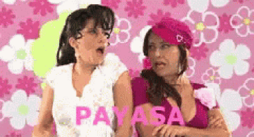 two women are standing next to each other on a pink background .