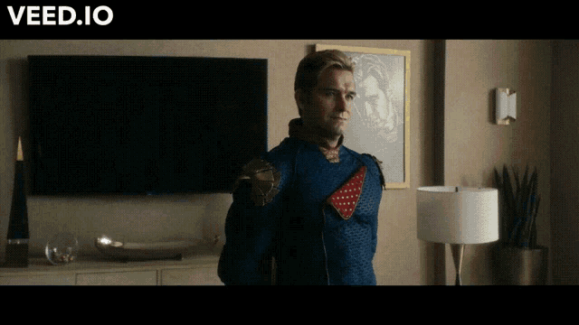 a man in a superhero costume is standing in front of a flat screen tv with the website veed.io below him