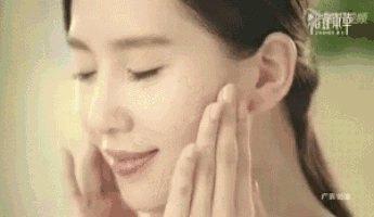 a woman is touching her face with her hands while smiling .