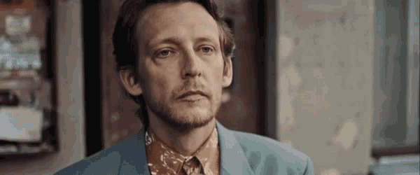 a man with a beard wearing a blue suit and a floral shirt .