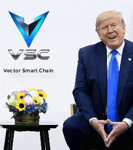 a man in a suit and tie sits in front of a sign that says ' vsc vector smart chain '