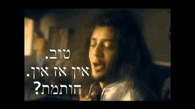 a man with long hair singing in a dark room