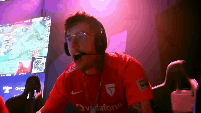 a man wearing headphones and a red shirt that says vodafone on it