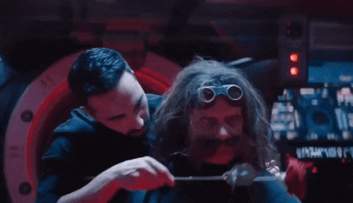 a man with a beard and goggles is holding a rose in front of another man with a beard .
