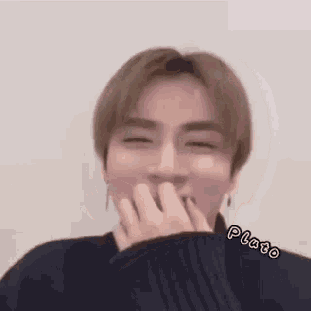 a man is covering his mouth with his hand and smiling .