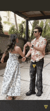 a man in a hawaiian shirt is dancing with a woman