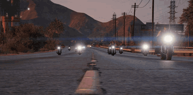 two motorcycles are driving down a road at night with mountains in the background