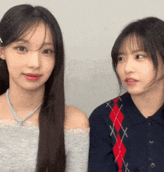 two girls are looking at each other with one wearing a plaid sweater