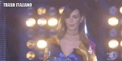 a woman in a colorful dress is standing on a stage in front of a microphone .