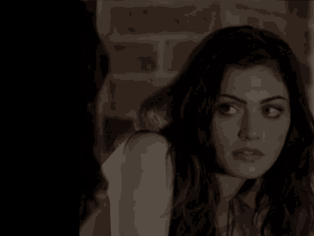 a woman is looking at another woman in a dark room