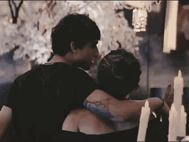 a man and a woman are hugging in front of candles .