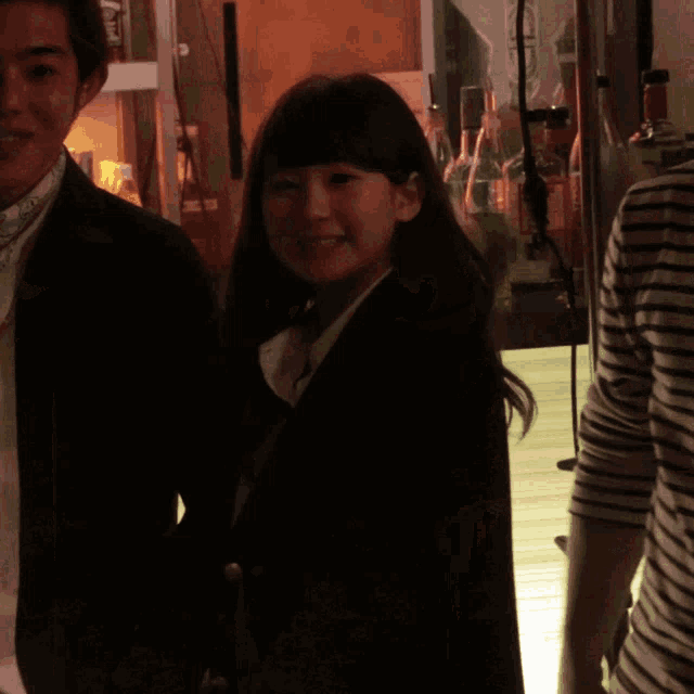 a woman in a black jacket smiles while standing next to a man in a black jacket