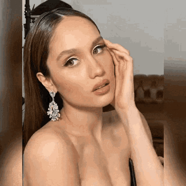 a woman wearing a black dress and earrings looks at the camera