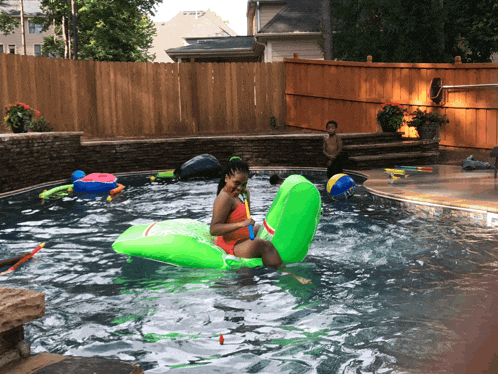 a girl in a red bikini is floating on a green watermelon float in a pool