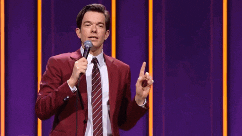 a man in a red suit and tie is speaking into a microphone