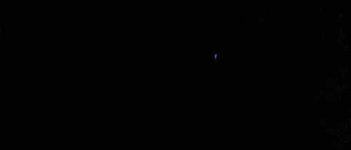 a crowd of people are raising their hands in the air in a dark room .