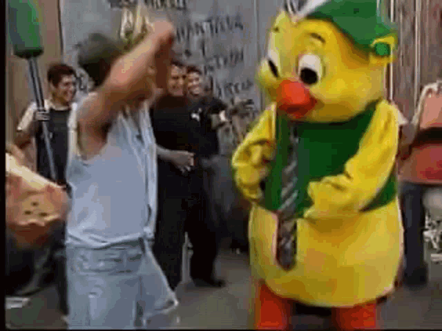 a man is standing next to a yellow chicken mascot