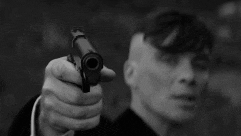 a man with a shaved head is holding a gun to his head .