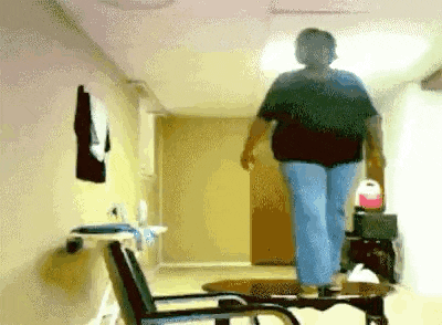 a woman in a black shirt is walking down a hallway next to a chair .