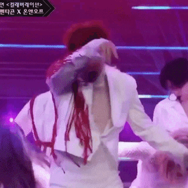 a man in a white suit is dancing on a stage in front of a sign that says ' x ' on it