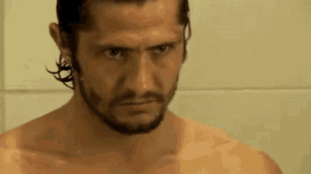 a shirtless man with a beard is standing in a shower .