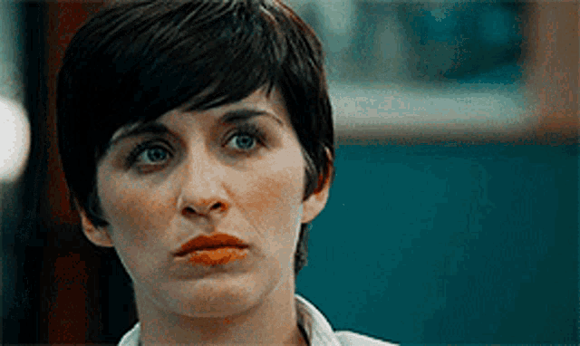 a close up of a woman 's face with short hair and a white shirt .