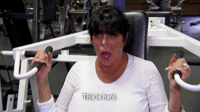 a woman in a white shirt is using a machine in a gym and says this is hard