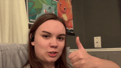 a woman is giving a thumbs up in front of a poster that says pokemon