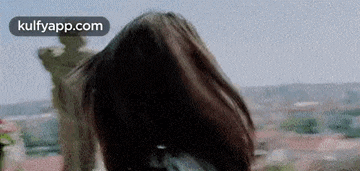 a woman with long hair is standing in front of a statue .