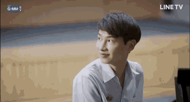 a young man in a white shirt is smiling in front of a line tv screen