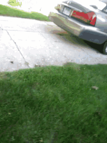 a car is parked on the side of the road next to a grassy area .