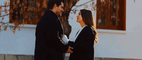 a man and a woman are standing next to each other and holding hands .