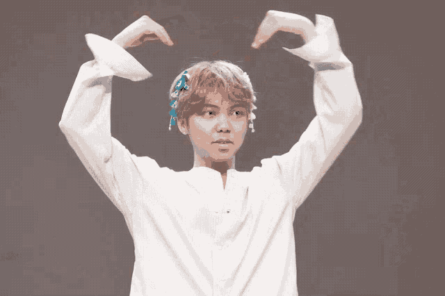 a person in a white shirt making a heart with their hands