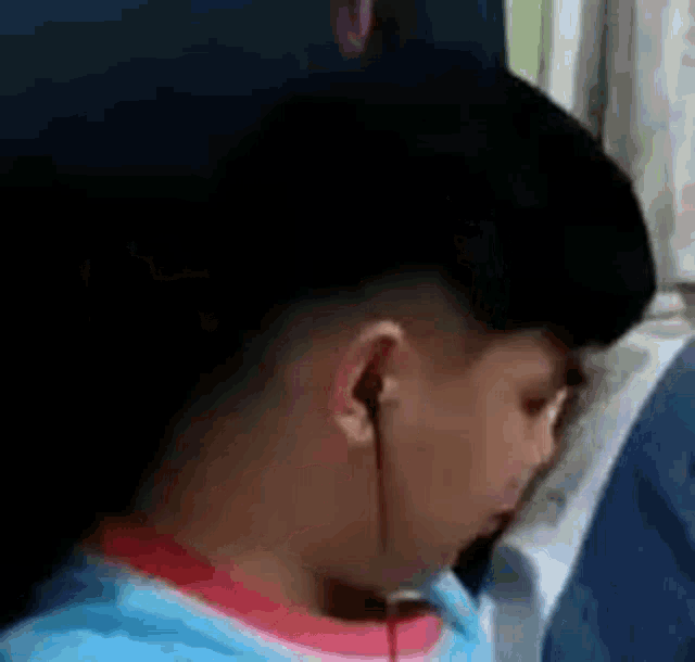 a young boy wearing ear buds is sleeping on a bus .
