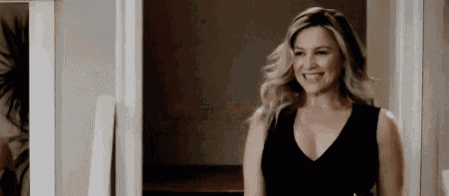 a woman in a black dress is smiling in a room .