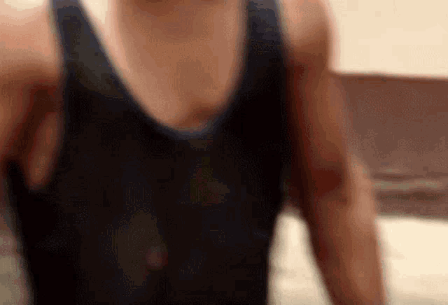 a man in a black tank top is standing with his arms outstretched .