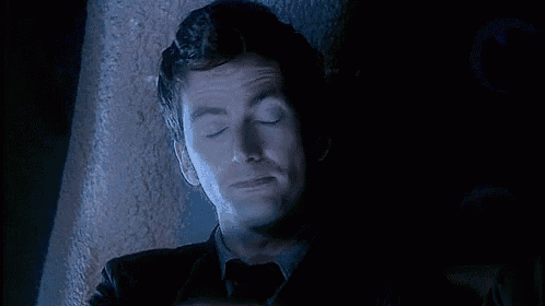 a man is laying down with his eyes closed in a dark room .