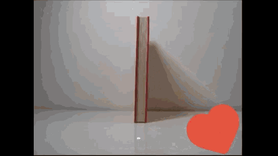 a book with a red spine is sitting on a white table next to an orange heart