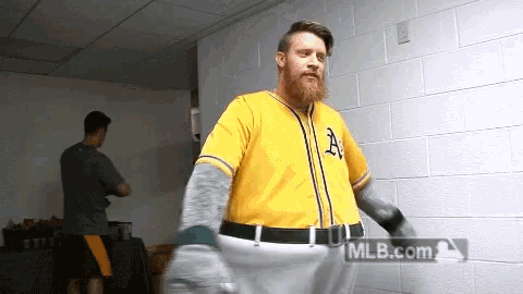 a man with a beard wearing a yellow a's jersey