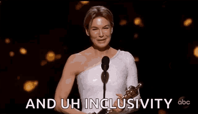 a woman in a white dress is standing in front of a microphone holding a trophy .