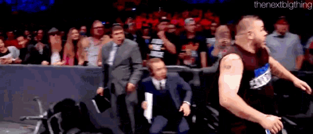 a man in a suit and tie is standing next to a man in a wheelchair in front of a crowd .