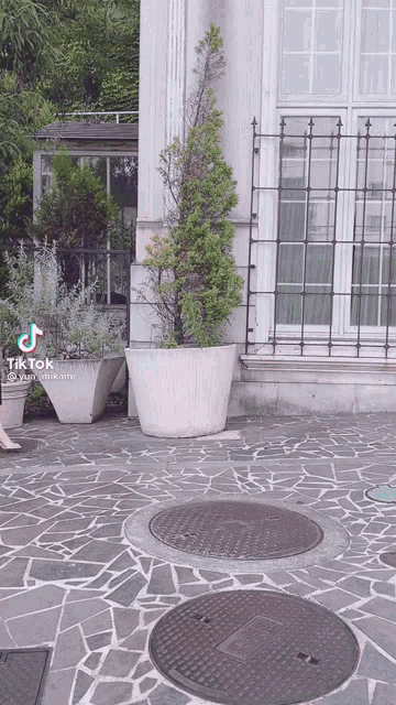 a manhole cover in front of a building that says tik tok on the bottom