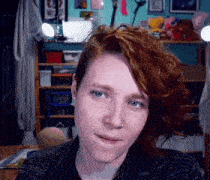 a woman with red hair and a nose ring is looking at the camera